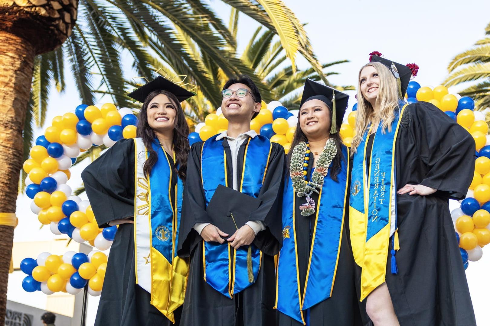 A group of 圣何塞州立大学 graduates pose for a photo dressed in their graduation cap and gown. 